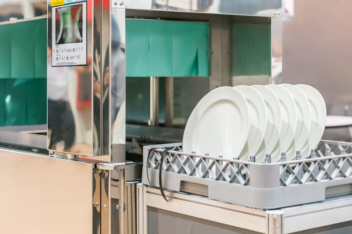 Białe talerze na koszu zmywarki gastronomicznej